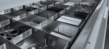 Sorted metal bins with barcodes and small parts as an example of efficient warehouse organisation and structured materials logistics